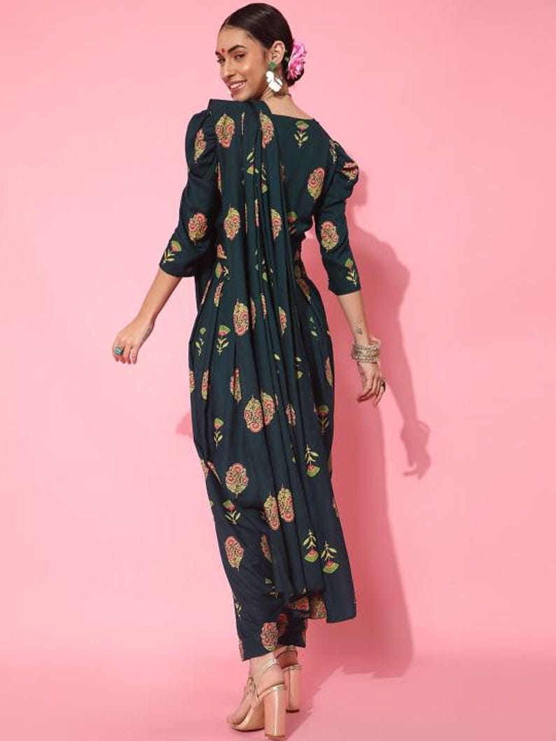 May include: A dark green printed dress with a floral pattern. The dress has a gathered skirt and a fitted bodice. The dress is worn with a matching printed dupatta.