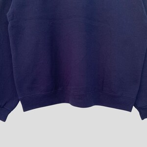 May include: A navy blue sweatshirt with long sleeves and a crew neck.