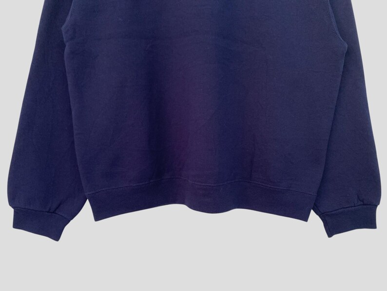 May include: A navy blue sweatshirt with long sleeves and a crew neck.