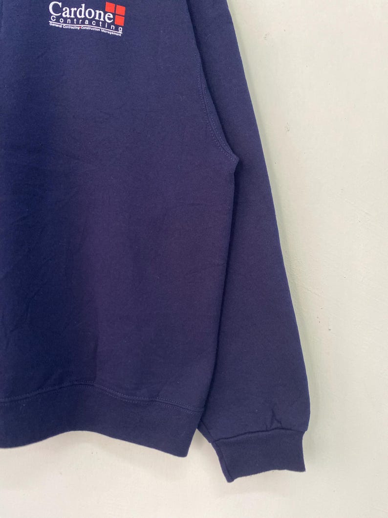 May include: A navy blue sweatshirt with the logo "Cardone Contracting" embroidered on the front in white and red.
