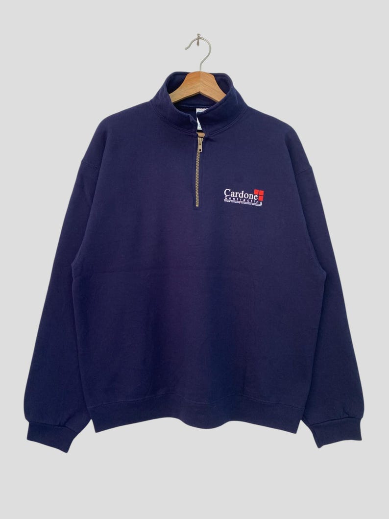 May include: A navy blue quarter-zip sweatshirt with the logo "Cardone Contracting" embroidered on the front.