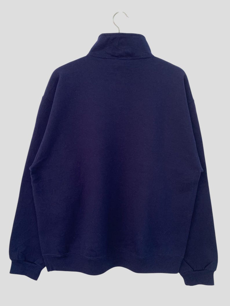 May include: A dark blue, long-sleeved sweatshirt with a mock neck and zipper closure.