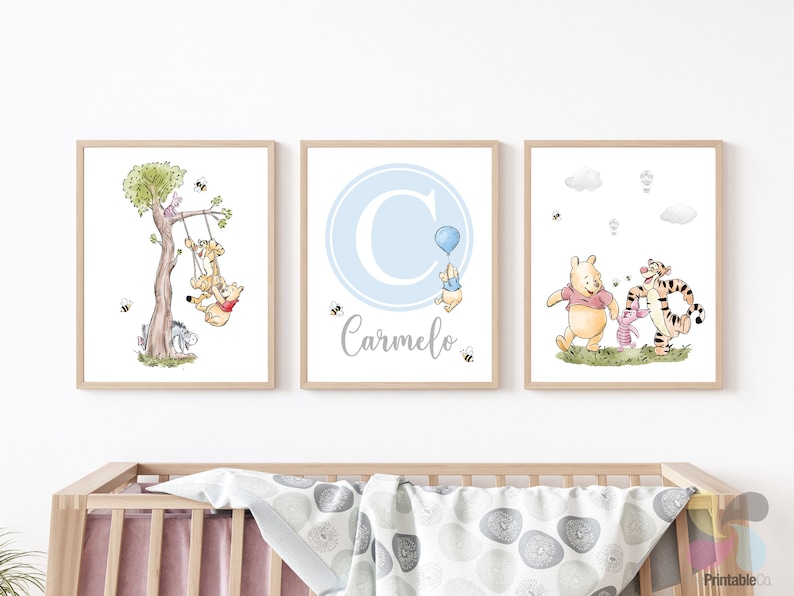 K&ouml;nnte beinhalten: Drei Winnie-the-Pooh-Kinderzimmerdrucke in einem blauen und grauen Farbschema. Der erste Druck zeigt Winnie Puuh, Ferkel und Tiger auf einer Schaukel. Der zweite Druck zeigt den Buchstaben C in einem blauen Kreis mit dem Namen Carmelo darunter. Der dritte Druck zeigt Winnie Puuh, Ferkel und Tiger, die zusammen gehen.