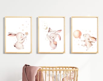 May include: Three watercolor prints featuring pink bunnies with different accessories. The first bunny is holding a flower, the second is holding a butterfly net, and the third is holding a balloon.