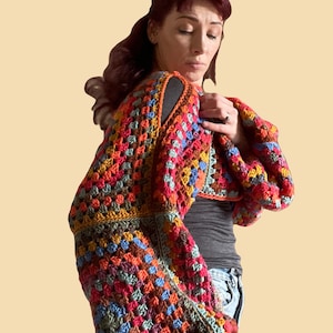 May include: A colorful crochet top with a granny square pattern in shades of red, orange, yellow, green, blue, and brown. The top has a cropped length and long, wide sleeves.
