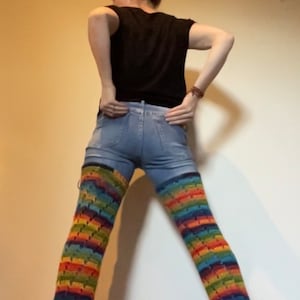 Puede incluir: Una persona con pantalones vaqueros azules y polainas de crochet arco&iacute;ris.