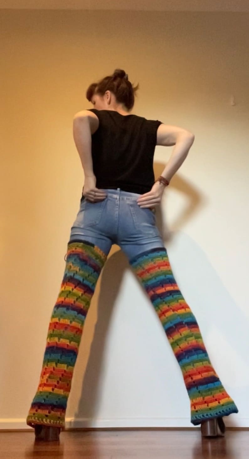 Puede incluir: Una persona con pantalones vaqueros azules y polainas de crochet arco&iacute;ris.