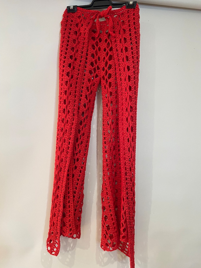 May include: Red crochet pants with a wide leg and a tie at the waist.