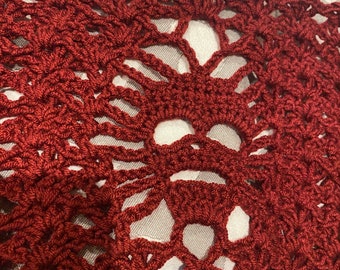 Puede incluir: Primer plano de un encaje de ganchillo rojo con un patrón delicado e intrincado. El encaje tiene un borde festoneado y está hecho con un hilo fino.