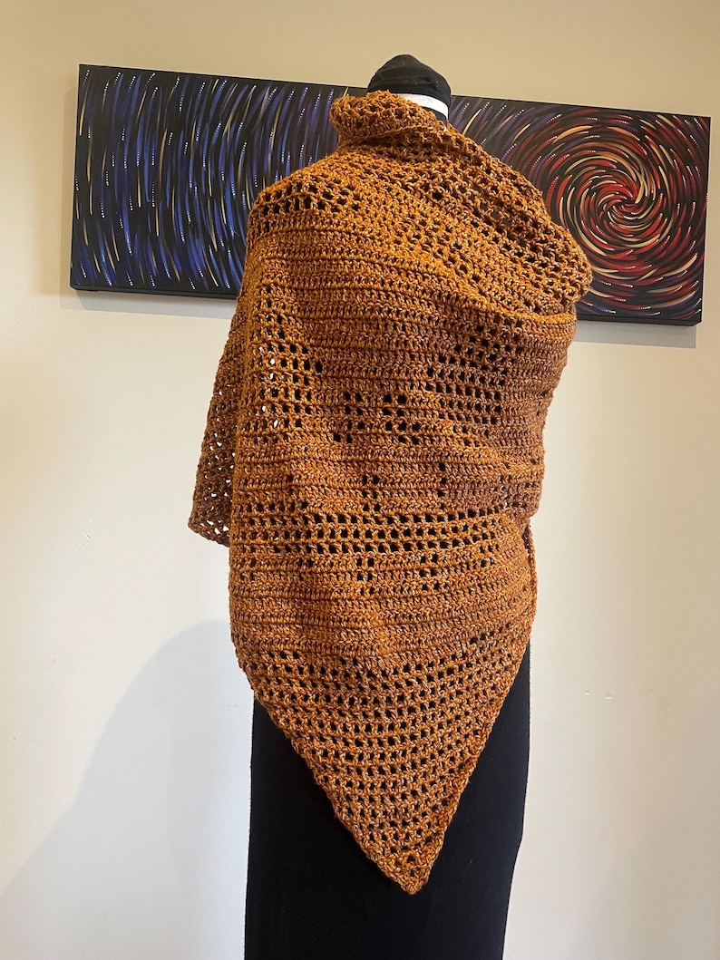 May include: A brown crocheted shawl with a triangular shape and a lacy pattern.