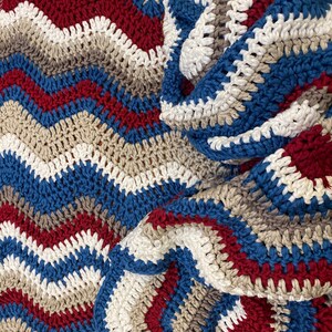 May include: A crocheted blanket with stripes of blue, white, grey, and red.