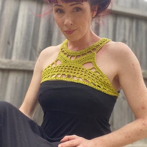 May include: A woman wearing a black maxi dress with a lime green crochet halter top.