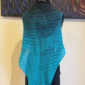 May include: A teal and black crochet shawl with a lacy pattern. The shawl is draped over a mannequin.