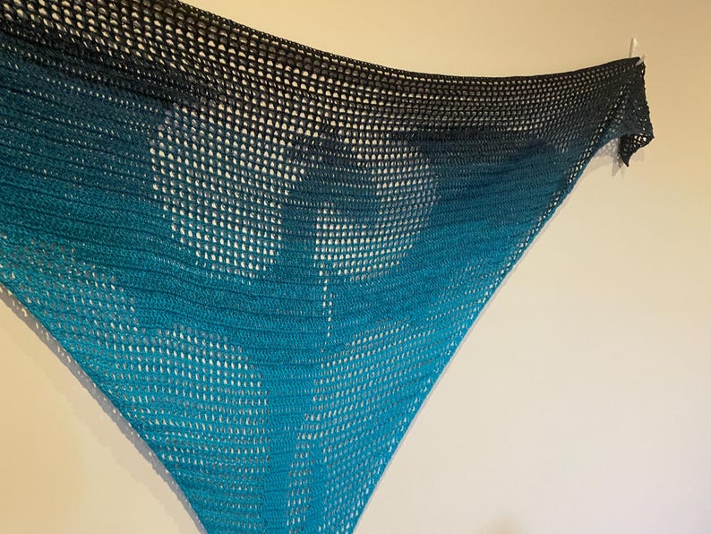 May include: A teal and black crocheted shawl with a gradient pattern. The shawl is made of a lightweight, open-weave fabric.