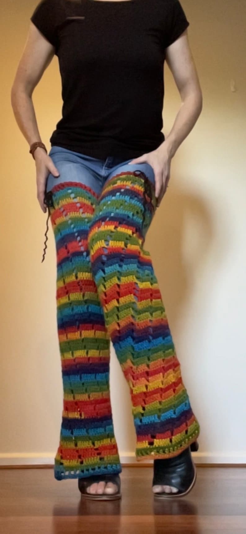 Puede incluir: Un par de polainas de crochet a rayas arco&iacute;ris con un patr&oacute;n de encaje. Las polainas se llevan sobre unos vaqueros azules.