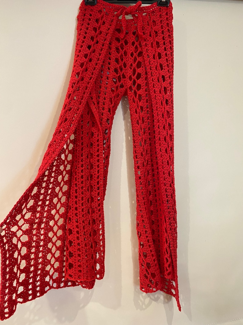 May include: Red crochet pants with a wide leg and a tie at the waist.