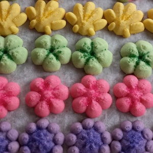 May include: Assortment of colorful sugar cookies decorated with sprinkles. The cookies are in the shapes of flowers and leaves.