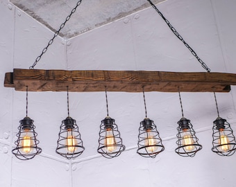 May include: A rustic wooden chandelier with six caged light bulbs. The chandelier is suspended from the ceiling by a chain.