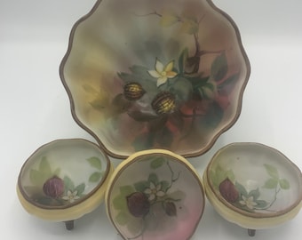 May include: A set of four vintage porcelain bowls with hand-painted floral designs. The bowls feature a delicate floral pattern with brown and white flowers and leaves. The larger bowl has a scalloped edge and the smaller bowls have three small feet.