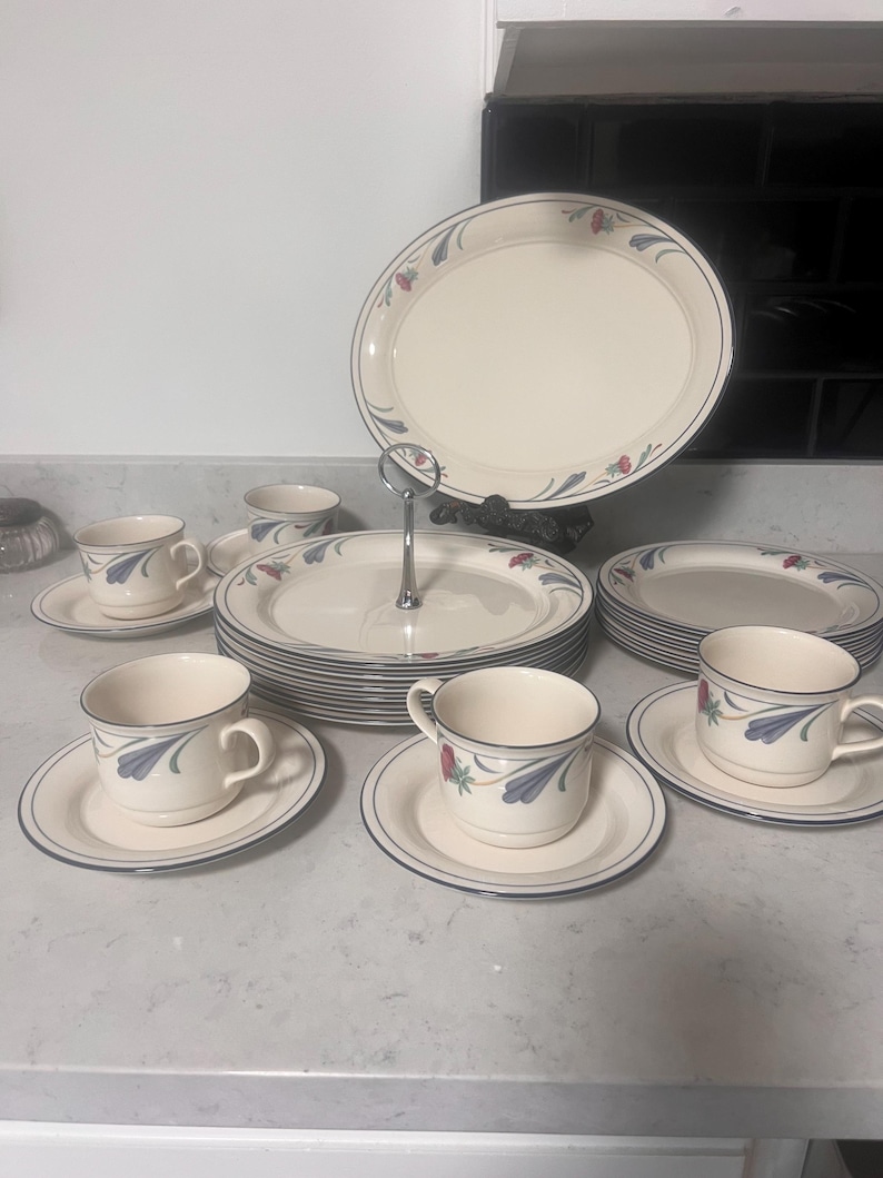 May include: A set of white ceramic dinnerware with a blue and red floral design. The set includes plates, cups, and saucers.