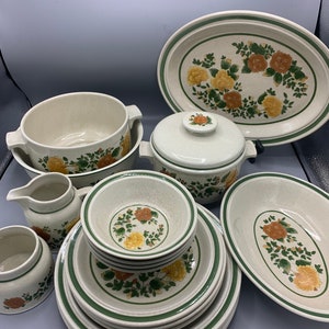 May include: A set of vintage stoneware dinnerware with a floral pattern in shades of green, yellow, and orange. The set includes a large oval serving platter, a covered casserole dish, a creamer, a sugar bowl, a soup bowl, and six dinner plates.