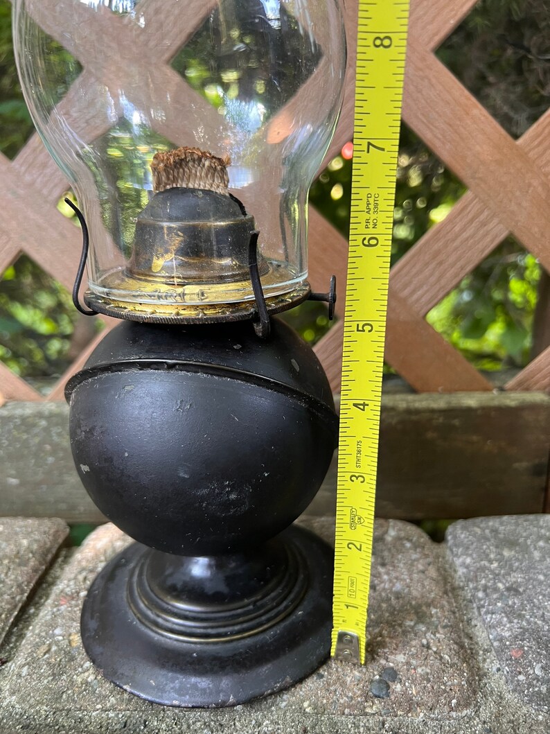 May include: A black oil lamp with a glass chimney and a brass burner. The lamp is about 7 inches tall.