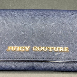 May include: A navy blue wallet with a gold metal Juicy Couture logo.