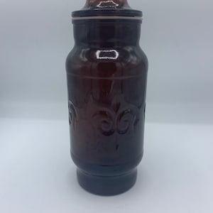 Vintage fleur de lis amber glass canisters, and one small root beer brown glass storage jars, one orange jar/urn