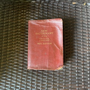 May include: A red, worn book with the title "New Dictionary of the English Language 1925 Edition" on the cover.