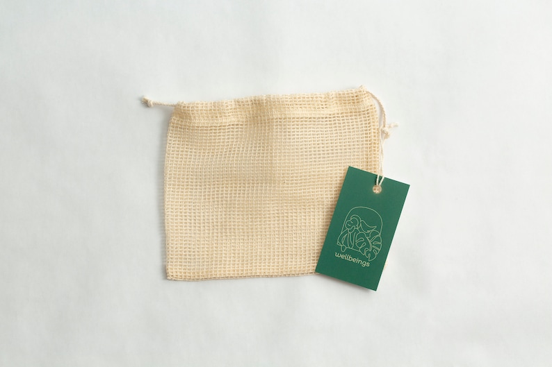 May include: A beige mesh produce bag with a green tag that says "wellbeings" and has a gold line drawing of a plant.