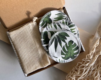 May include: A set of reusable makeup remover pads in a cardboard box. The pads are white with a green tropical leaf print. The box also contains a small mesh bag.