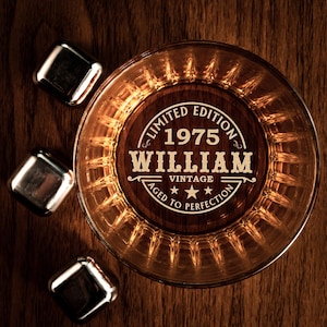 May include: A round glass whiskey tumbler with a wooden coaster that says "Limited Edition 1975 William Vintage Aged to Perfection".