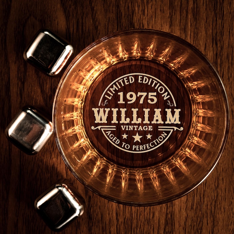 May include: A round glass whiskey tumbler with a wooden coaster that says "Limited Edition 1975 William Vintage Aged to Perfection".