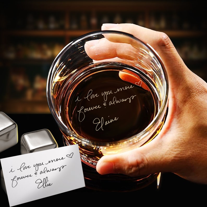 Puede incluir: Un vaso transparente con un mensaje escrito a mano en el interior que dice "Te amo m&aacute;s para siempre y siempre Elaine". El vaso est&aacute; lleno de un l&iacute;quido &aacute;mbar oscuro y est&aacute; siendo sostenido por una mano.