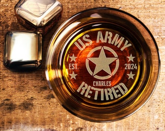 May include: A clear glass with a brown liquid inside. The glass has an etched design that says "US ARMY EST. 2024 CHARLES RETIRED" with a star in the centre.