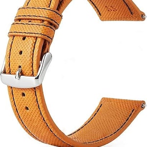 May include: A tan watch strap with a textured surface and black stitching. The strap features a silver buckle and is designed to attach to a watch face. The strap is made of a durable material.