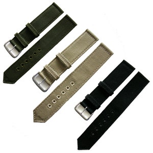 May include: Four watch straps in different colors: green, beige, black, and dark green. The straps are made of a canvas material and have a stitched design. The straps have silver buckles.