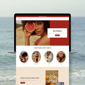 May include: A website homepage for a clothing store featuring a woman holding a grapefruit in front of her eye. The website has a red and white color scheme and features a section for new arrivals, best sellers, and sales. The text "Elegant Design, Expertly Crafted" is displayed on the website.