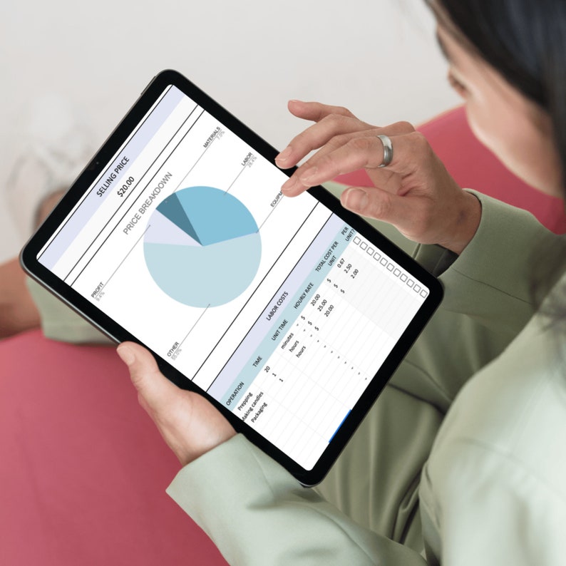 May include: A person holding a black tablet displaying a price breakdown chart with a pie chart and data tables. The chart includes sections for profit, labor, materials, and other costs. The tablet screen shows the selling price as $20.00.