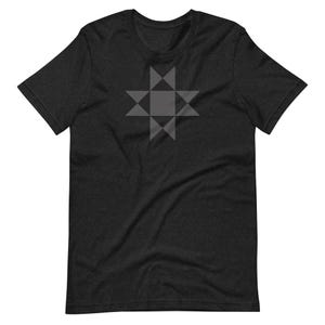May include: Dark gray t-shirt featuring a geometric star design in a lighter shade of gray. The star is centered on the chest and composed of triangles and squares. The shirt has short sleeves and a crew neck.