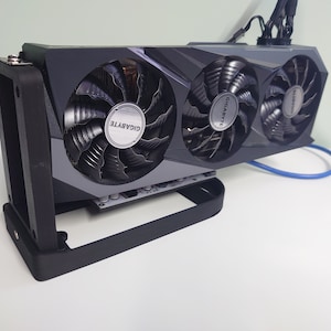 May include: A black graphics card with three fans. The fans feature the Gigabyte logo. The card is mounted in a black metal bracket.
