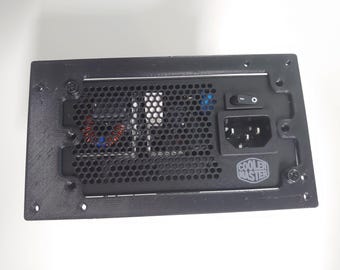 May include: Black computer power supply with a mesh vent, power switch, and power input. The Cooler Master logo is visible. The unit has screw holes for mounting.