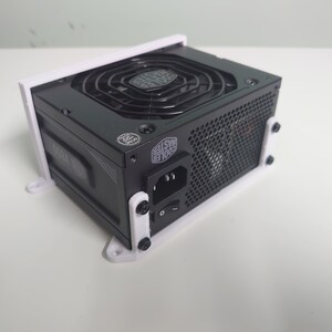 K&ouml;nnte beinhalten: Ein schwarzes Netzteil f&uuml;r Computer mit einer wei&szlig;en Kunststoffhalterung. Das Netzteil hat einen gro&szlig;en L&uuml;fter und ein schwarzes Netzkabel.