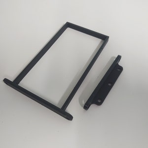 K&ouml;nnte beinhalten: Zwei schwarze, 3D-gedruckte Kunststoffteile f&uuml;r ein Projekt. Ein Teil ist ein rechteckiger Rahmen, der andere ist ein kleineres, flaches St&uuml;ck mit drei L&ouml;chern.