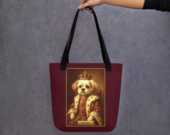 Puede incluir: Un bolso tote de color granate con un gráfico rectangular de un perro con una corona dorada y una túnica real roja con ribete de piel. El perro está sentado en un trono y una pequeña placa dorada en la parte inferior muestra el texto KHABBA.