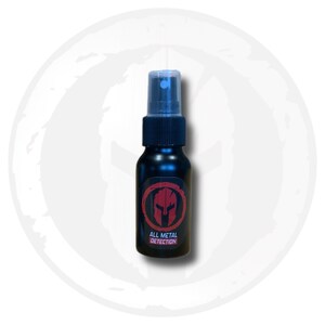 May include: A black spray bottle with a clear cap. The bottle has a red and black label with a Spartan helmet design and the text "ALL METAL DETECTION". The bottle is centered on a white background.