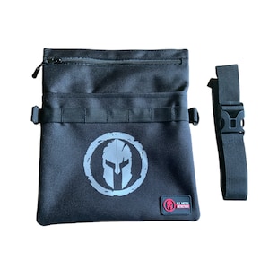 May include: Black canvas utility bag with a zipped top, a strap, and a silver Spartan helmet logo. The bag has a red label that says "All Metal Detection".