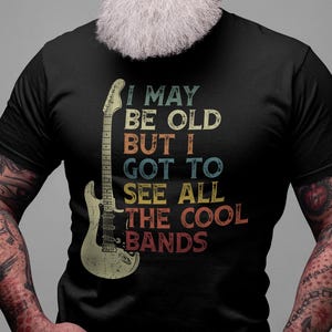 May include: A black t-shirt with a vintage-style graphic of an electric guitar and the text "I may be old but I got to see all the cool bands".