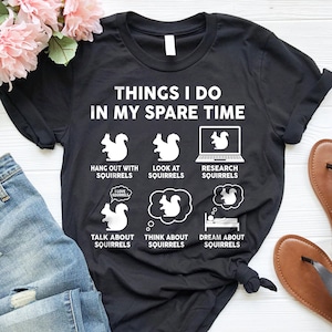May include: Black t-shirt with white text that reads "Things I do in my spare time". The text is surrounded by six white illustrations of squirrels doing various activities, including hanging out, looking at a laptop, talking, thinking, and sleeping.