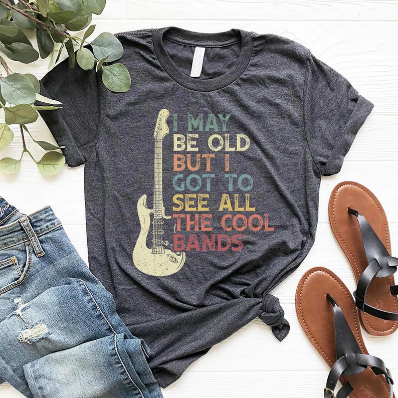 May include: A dark grey t-shirt with a vintage-style graphic of an electric guitar and the text "I may be old but I got to see all the cool bands".